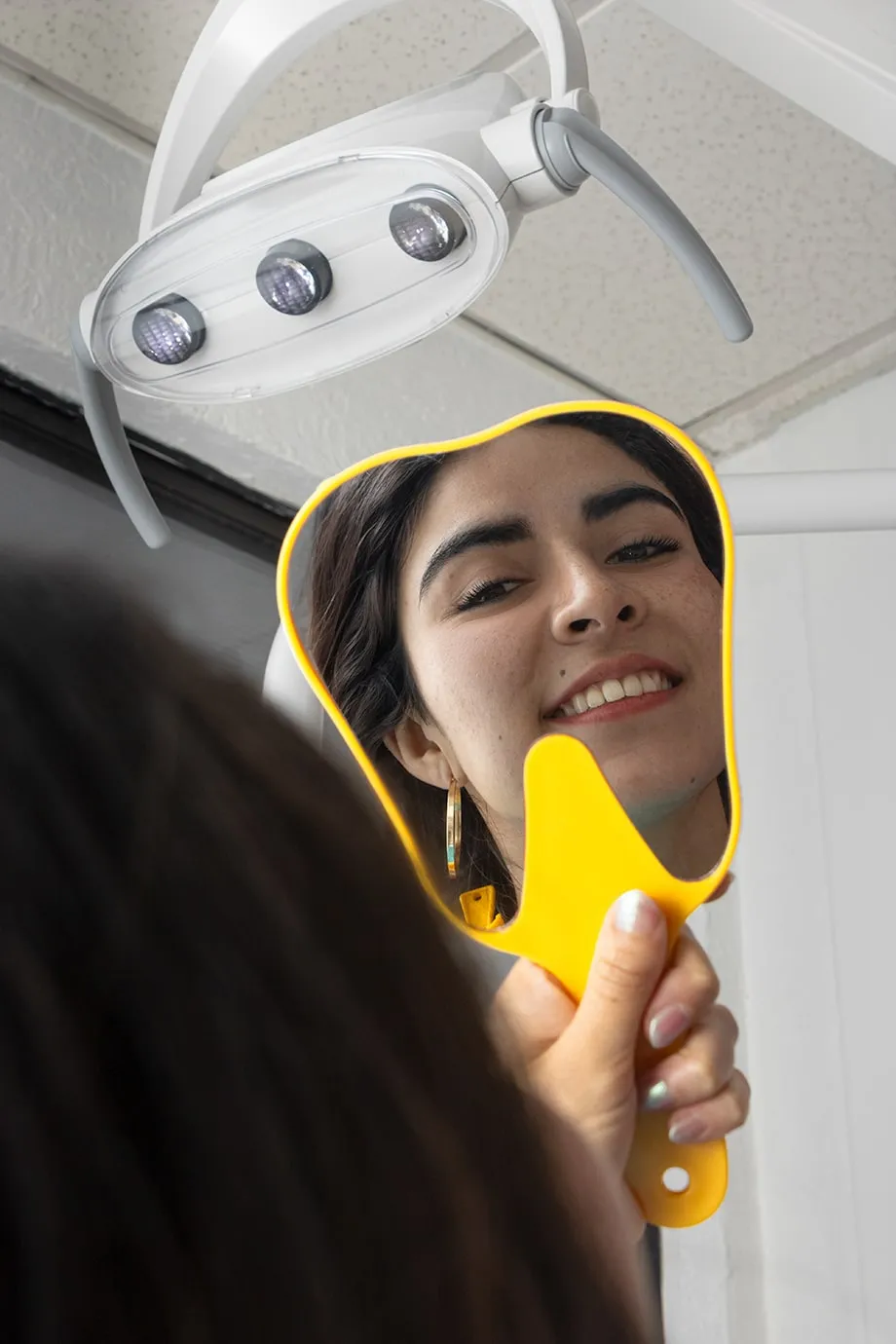 Paciente sonriendo frente al espejo después de su tratamiento